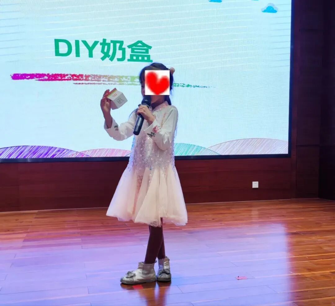 小朋友在舞台上展示自己DIY的牛奶盒作品