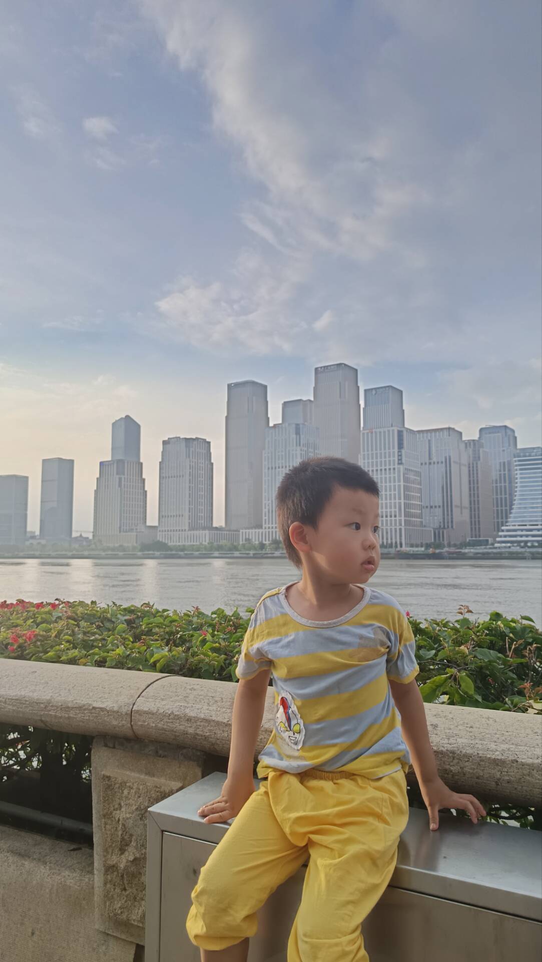 广州有轨电车沿线,孩子坐在珠江边石栏上看江景